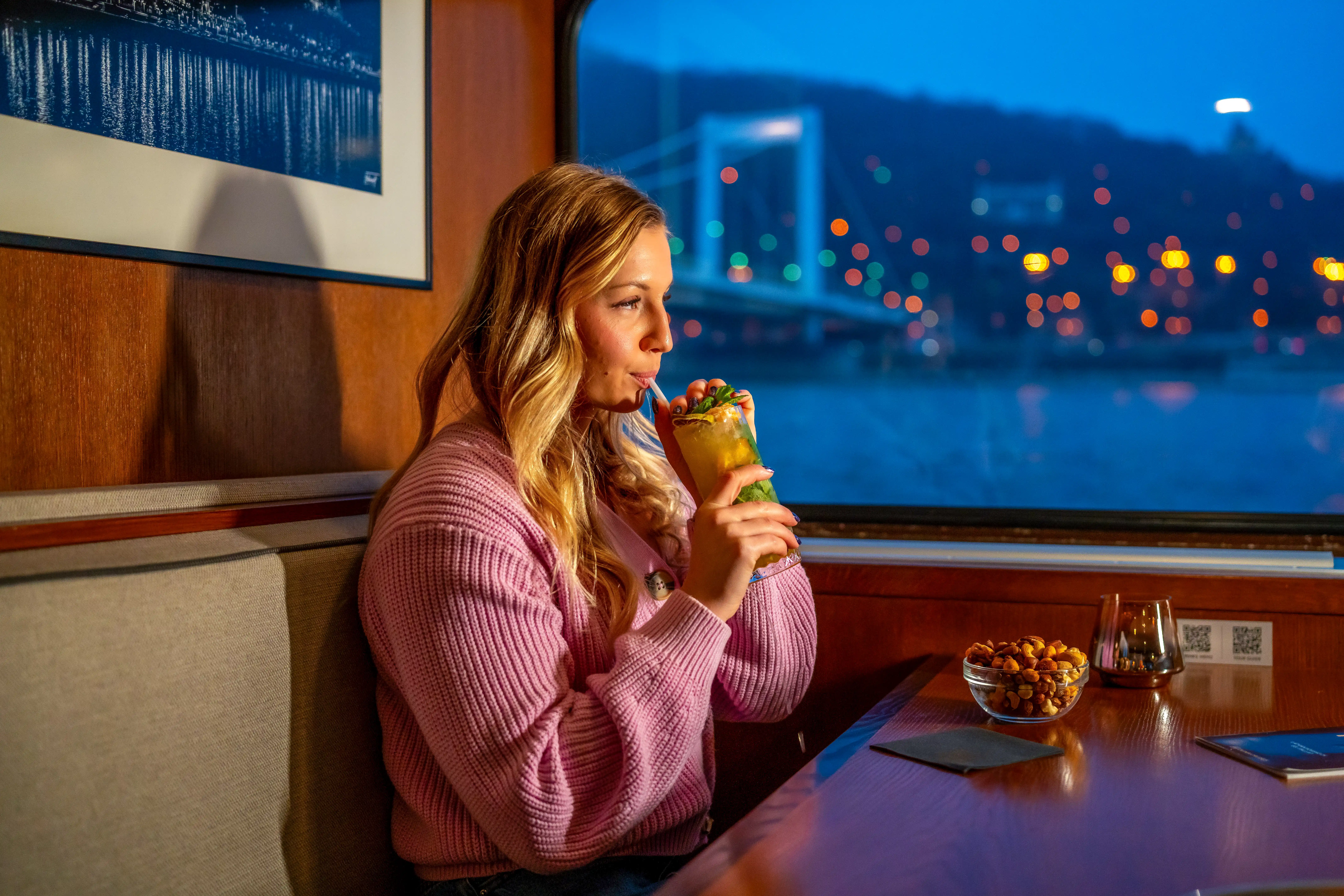 View of the illuminated Budapest through the window of an indoor river cruise during a rainy evening
indoor river cruise cabin with large panoramic windows and blankets for bad weather sightseeing
